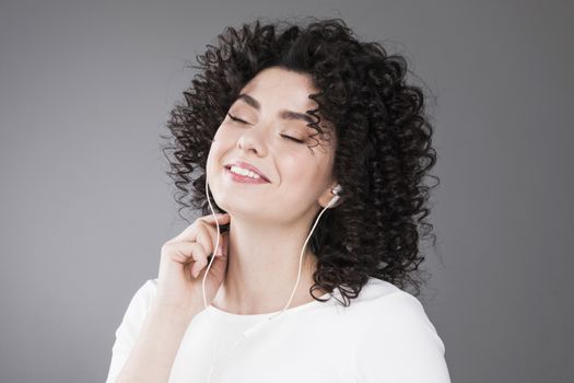 Portrait of beautiful smiling woman with curly hair, gray background