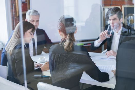 Business colleagues meeting in conference room, shot through glass