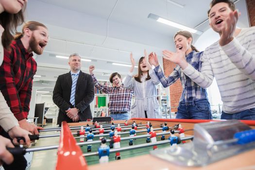 Group of happy people playing table soccer together