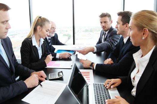 Mixed group of people in business meeting working with documents and computers