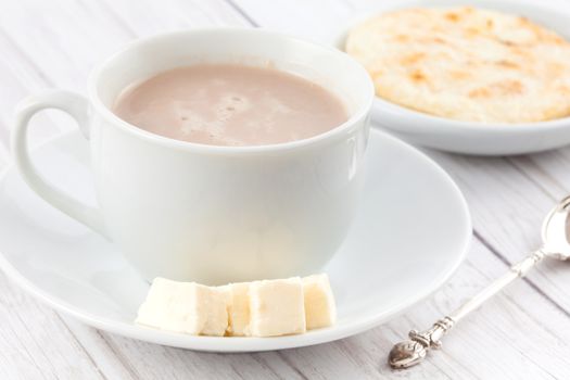 Cup of hot chocolate with cheese and arepa served in white dishware