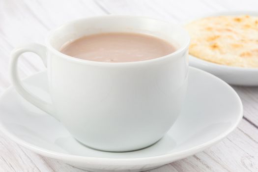 Cup of hot chocolate with cheese and arepa served in white dishware