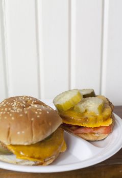 Two vegetarian cheeseburgers with pickles and tomatoes on a plate