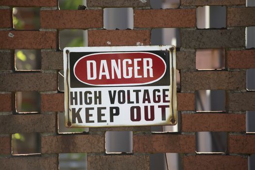 Danger high voltage keep out sign on a red brick wall