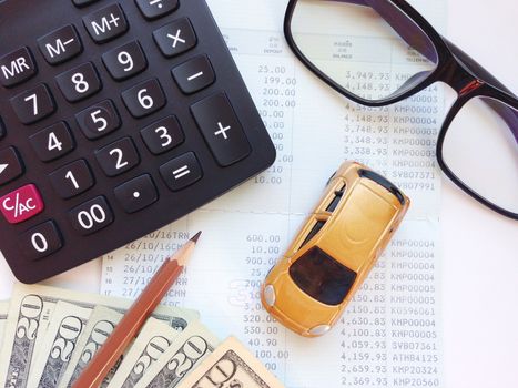 Business, finance, saving money, banking or car loan concept : Miniature car model, calculator, dollar money and saving account book or financial statement on office table