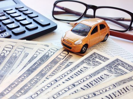 Business, finance, saving money, banking or car loan concept : Miniature car model, calculator, dollar money, eyeglasses, pencil and saving account book or financial statement on office desk table