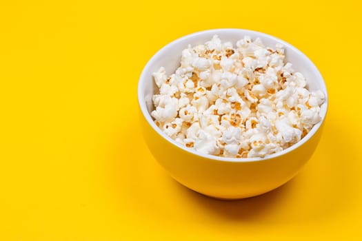 Bowl of Delicious Popcorn spilling onto a yellow background