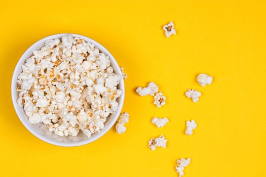 Bowl of Delicious Popcorn spilling onto a yellow background