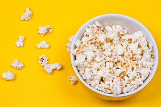 Bowl of Delicious Popcorn spilling onto a yellow background