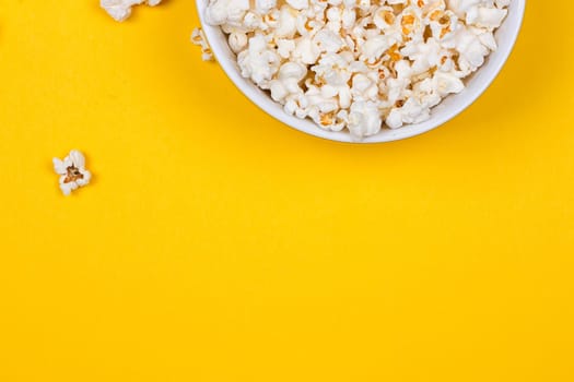 Bowl of Delicious Popcorn spilling onto a yellow background