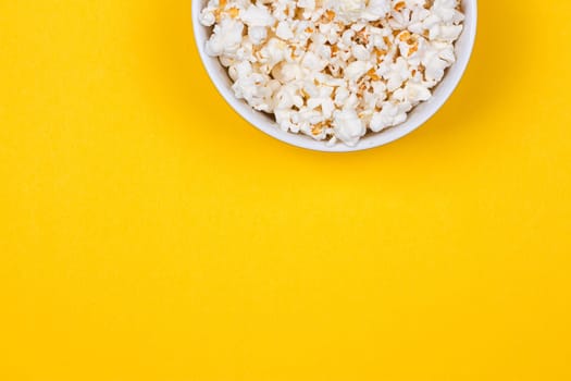 Bowl of Delicious Popcorn spilling onto a yellow background