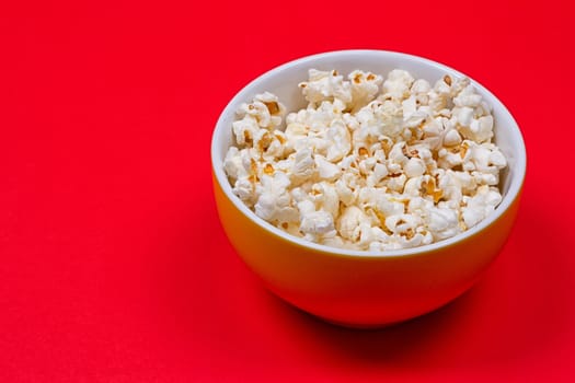 Bowl of Delicious Popcorn spilling onto a red background