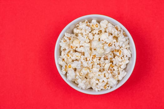 Bowl of Delicious Popcorn spilling onto a red background