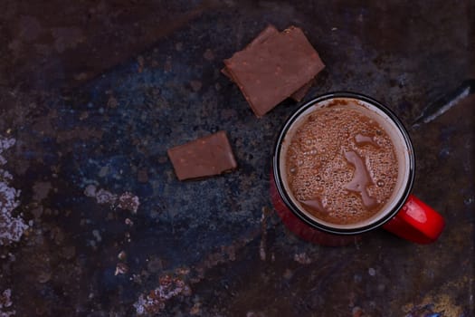 Hot chocolate in mug with chocolate on grunge dark table