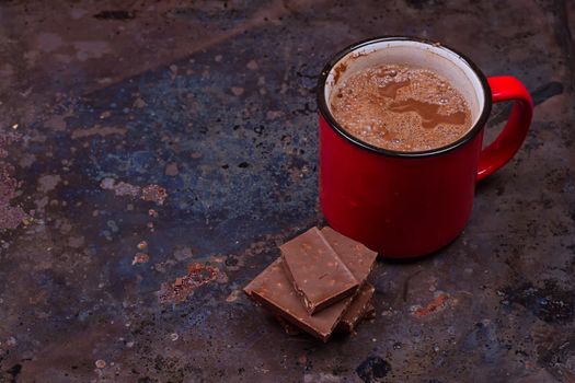 Hot chocolate in mug with chocolate on grunge dark table