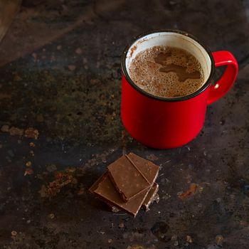 Hot chocolate in mug with chocolate on grunge dark table