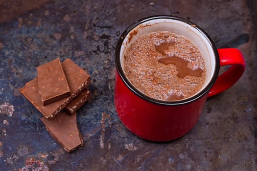 Hot chocolate in mug with chocolate on grunge dark table