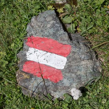 Walking path sign in Austria, flag painted on a rock
