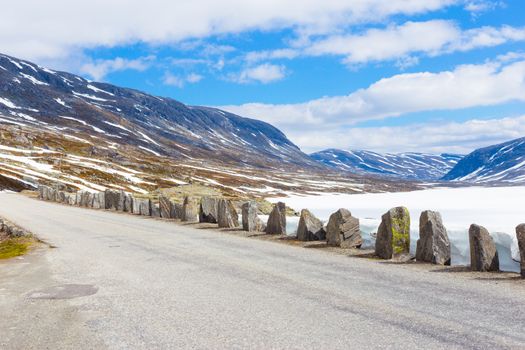 Old road with stones in summer with snow in Norway mountains