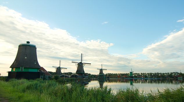 Famous Zaanse Schans Windmills from River Coast with Reflection on Water Early Morning Outdoors