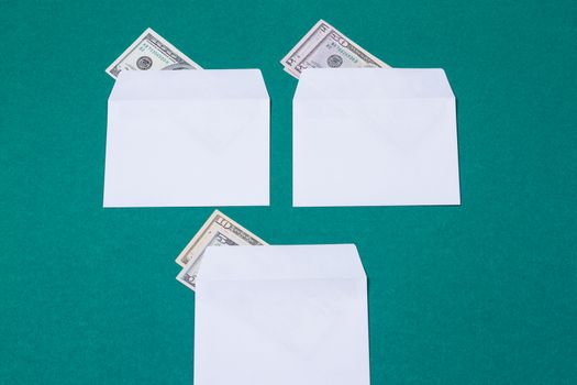 three white envelopes with money on green background