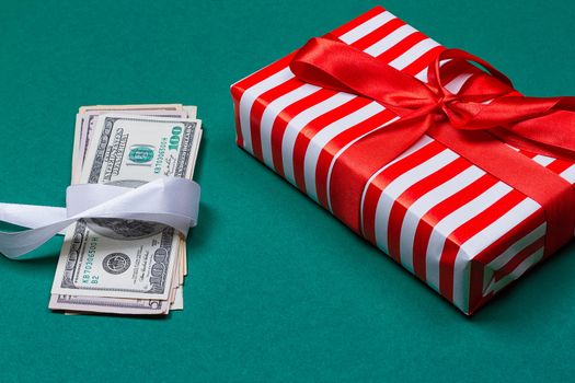 Concept: a gift or money. american money with gift box on a green background