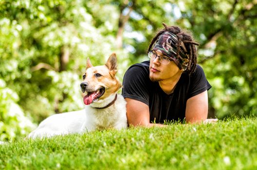 caucasian guy is laying on the grass with his dog