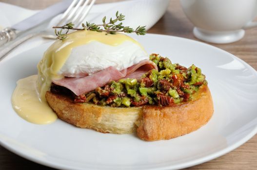 Toasted baguette slice with guacamole, ham and eggs Benedict under Dutch sauce
