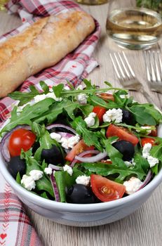 Variation of Greek salad with arugula, cherry slices, feta and olives