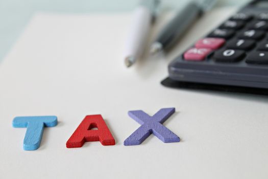 Business, finance, saving money, banking, loan, investment, taxes or accounting concept : Calculator, pens and tax wooden word on office desk table