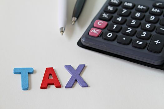 Business, finance, saving money, banking, loan, investment, taxes or accounting concept : Calculator, pens and tax wooden word on office desk table