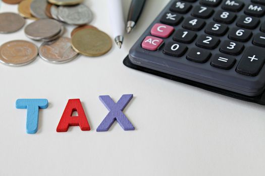 Business, finance, saving money, banking, loan, investment, taxes or accounting concept : Wooden word TAX, coins and calculator on office desk table