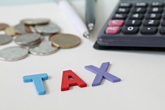 Business, finance, saving money, investment, taxes or accounting concept : Wooden word TAX, coins and calculator on office desk table