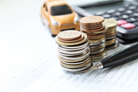 Business, finance, saving money or car loan concept : Miniature car model, calculator, coins and saving account book or financial statement on office desk table