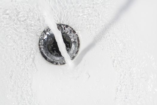 Fresh water running down the drain of a ceramic washbasin