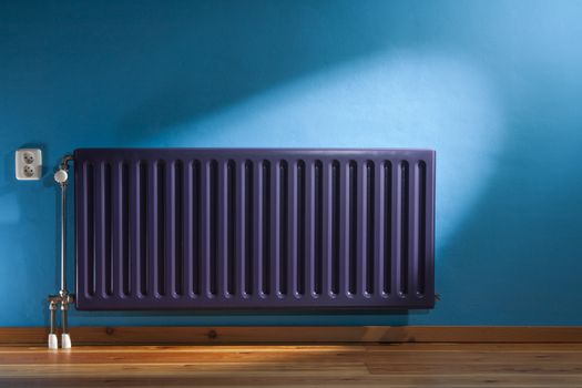 Purple central heating radiator and a blue wall with power point in the Netherlands