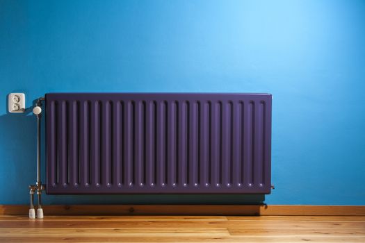 Purple central heating radiator and a blue wall with power point in the Netherlands