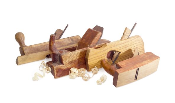 Several old wooden hand planes different special purposes and shavings on a white background
