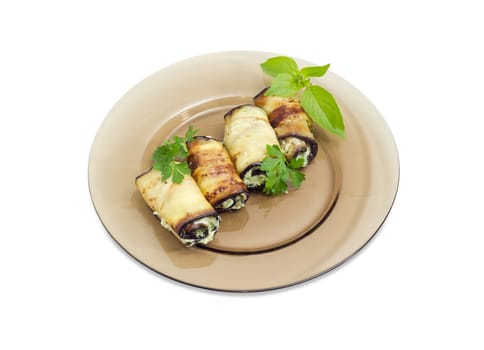 Eggplant rolls with tuna and processed cheese filling decorated with parsley and basil twigs on a dark glass dish on a white background
