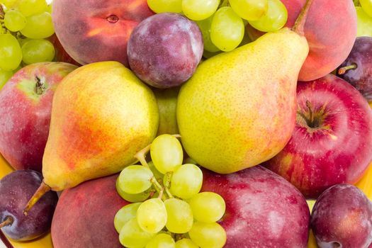 Background of a pile of the apples, pears, plums, peaches and clusters of white grapes 
