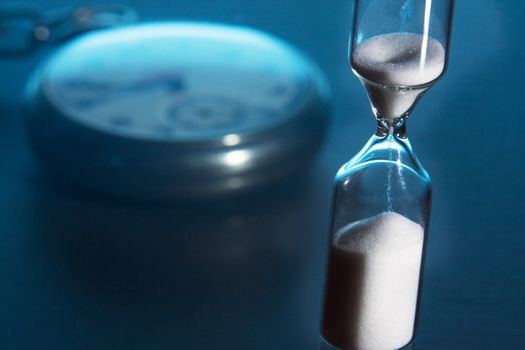 Hourglass and pocket watch with blue background