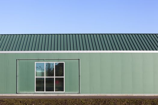 Green industrial building with a metal frame and a window