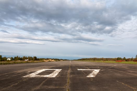 Plane runway, airstrip in the airport terminal with marking on blue sky with clouds to use as background. Travel aviation and holiday concept. Soft focus