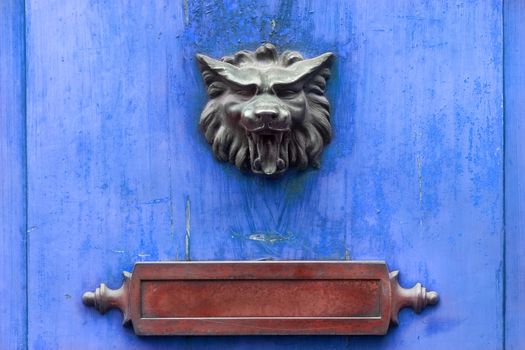 Metal doorknocker and red letter box on a blue wooden door