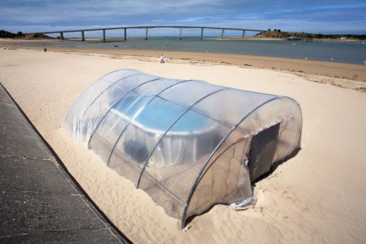 Very small indoor swimming pool on the beach of Fromentine in France. The bridge, pont of Noirmoutier, in the background