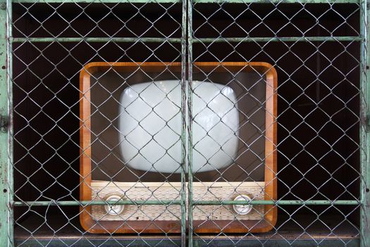 Vintage television in a retro green metal closet with netting