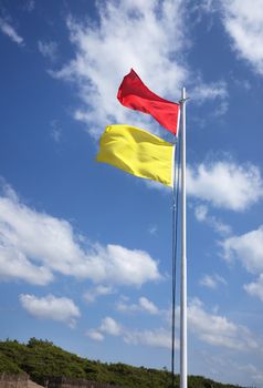 red and yellow safe bathing area flag against sky