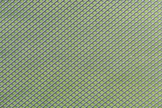 Grey metal wire mesh work against a green background as a background picture
