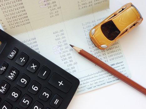 Business, finance, saving money, banking or car loan concept : Miniature car model, calculator and saving account book or financial statement on office table