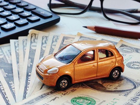 Business, finance, saving money, banking or car loan concept : Miniature car model, calculator, dollar money and saving account book or financial statement on office desk table